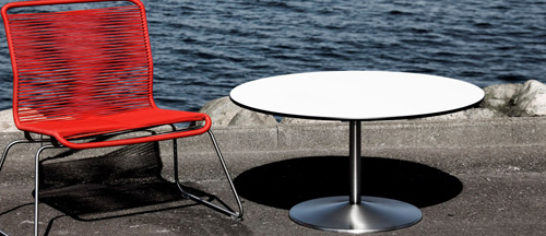 VP Table er et enkeltsøjlet bord med en rund pyramideformet fod – her flankeret af Verner Pantons Tivoli-stolen, også fra DJOB. 